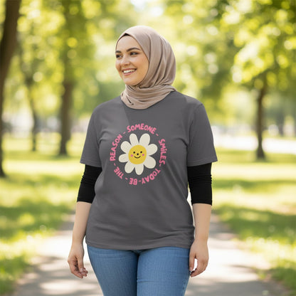 Jena Jewelry charcoal grey cotton t-shirt with a smiling daisy graphic and the text “Be the Reason Someone Smiles Today”