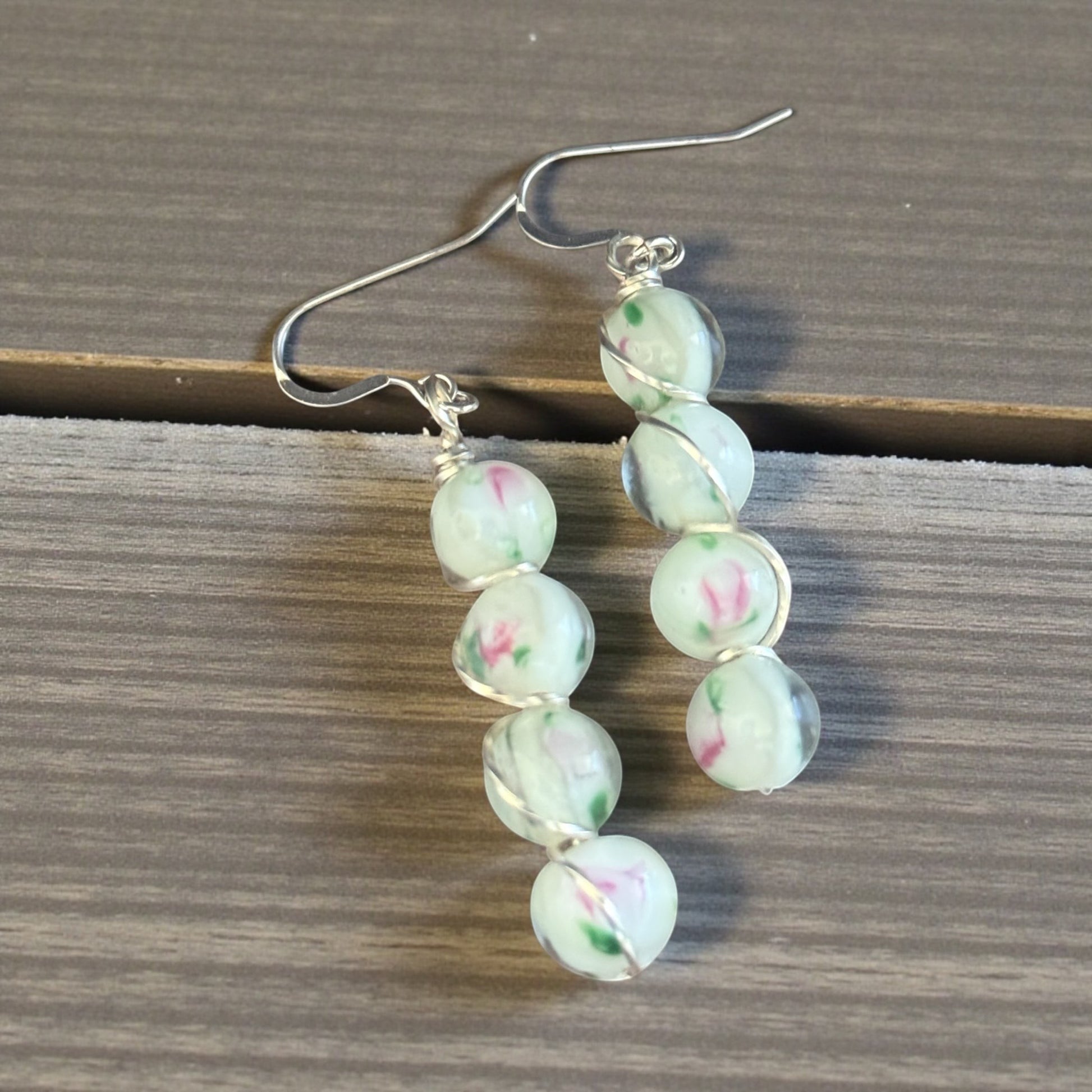 Jena Jewelry stacked drop earrings with light green beads featuring pink floral designs, wire-wrapped with silver-tone accents.