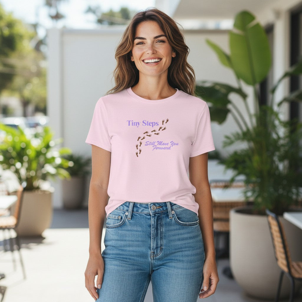 Jena Jewelry light pink 100% cotton t-shirt with "Tiny Steps" and footprints graphic. "Still Move You Forward" text below.