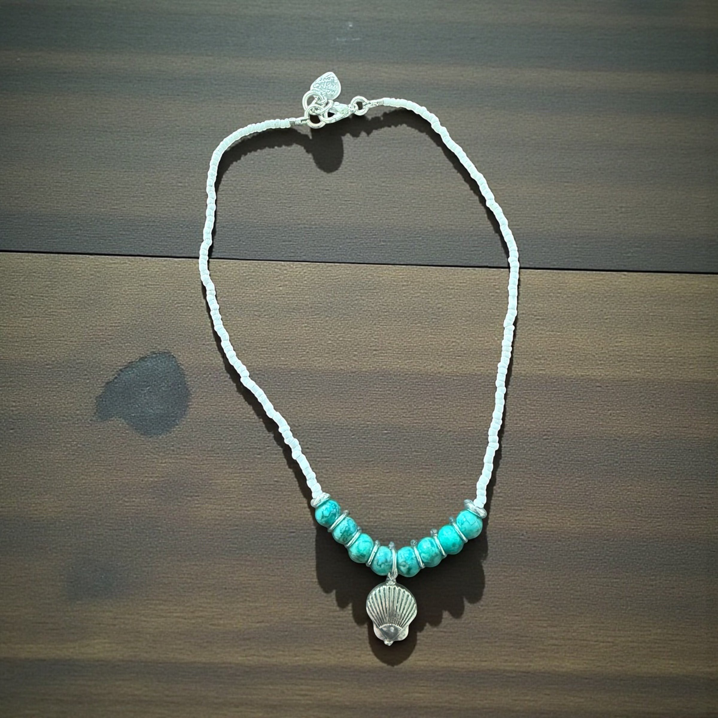 Jena Jewelry white seed bead necklace with turquoise beads and seashell charm, evoking coastal calm and ocean energy.