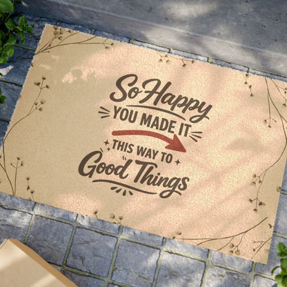 Jena Jewelry natural coir doormat with "So Happy You Made It This Way To Good Things" text and decorative branches.
