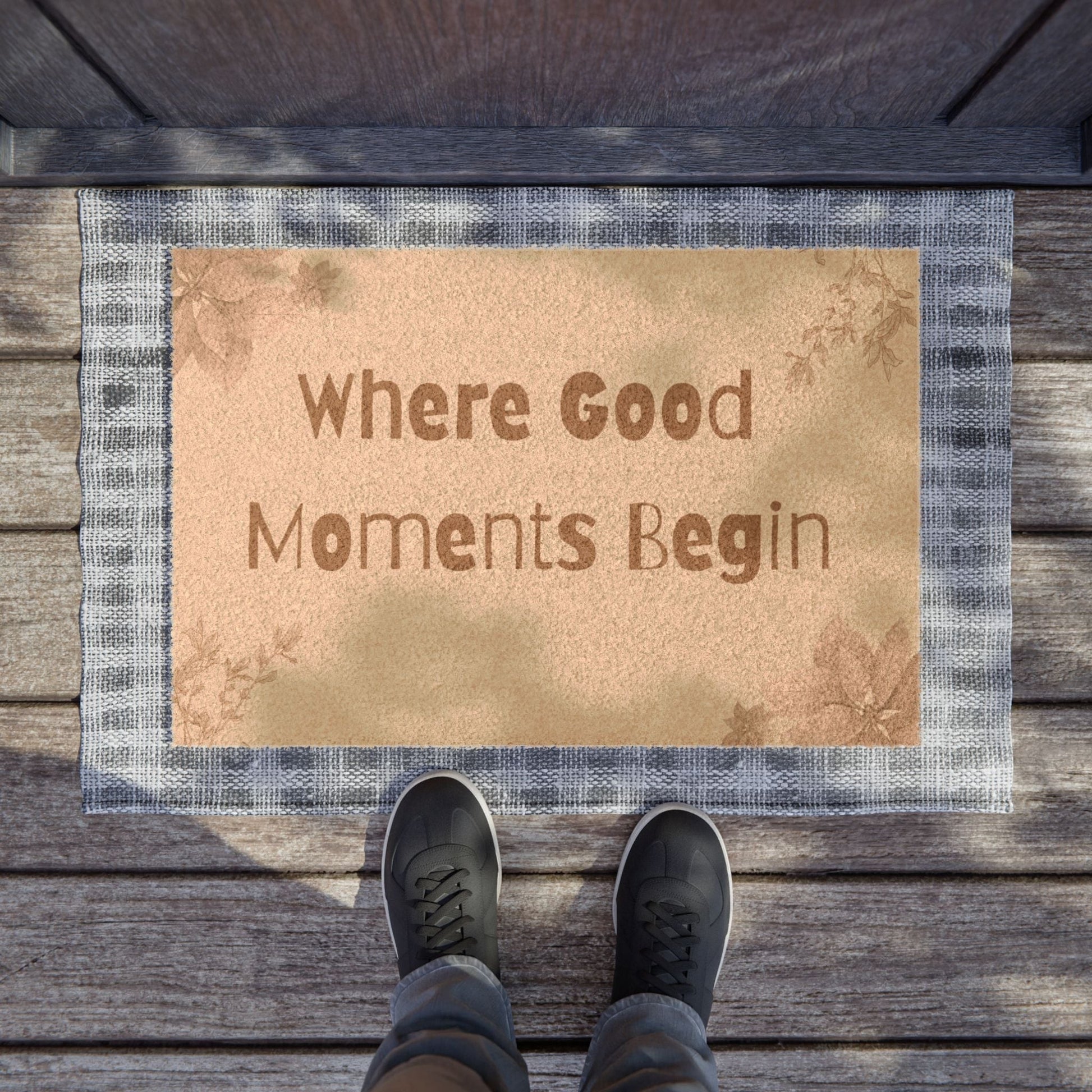 Jena Jewelry floral welcome doormat with "Where Good Moments Begin" text, made of natural coir with a grey plaid border.