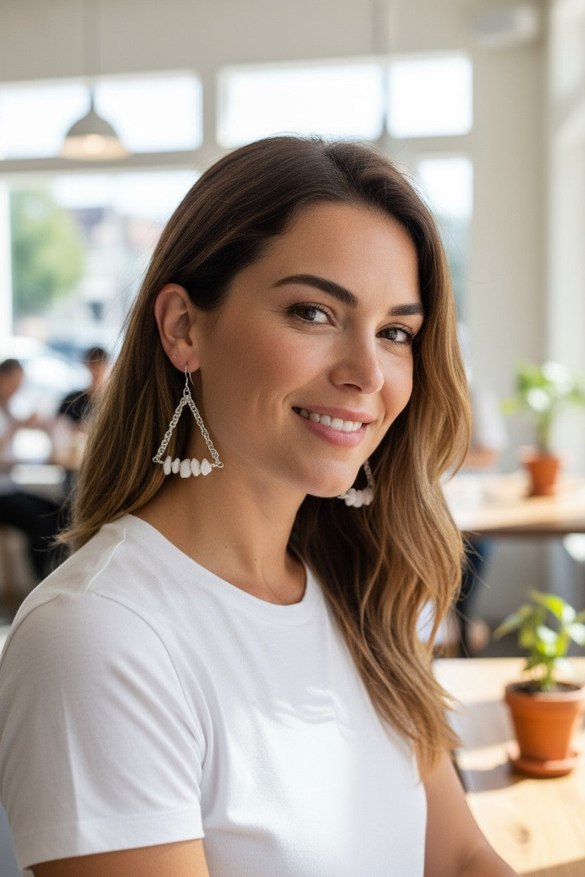 Jena Jewelry white stone and silver chainmaille triangle earrings worn by a smiling woman in a white t-shirt.