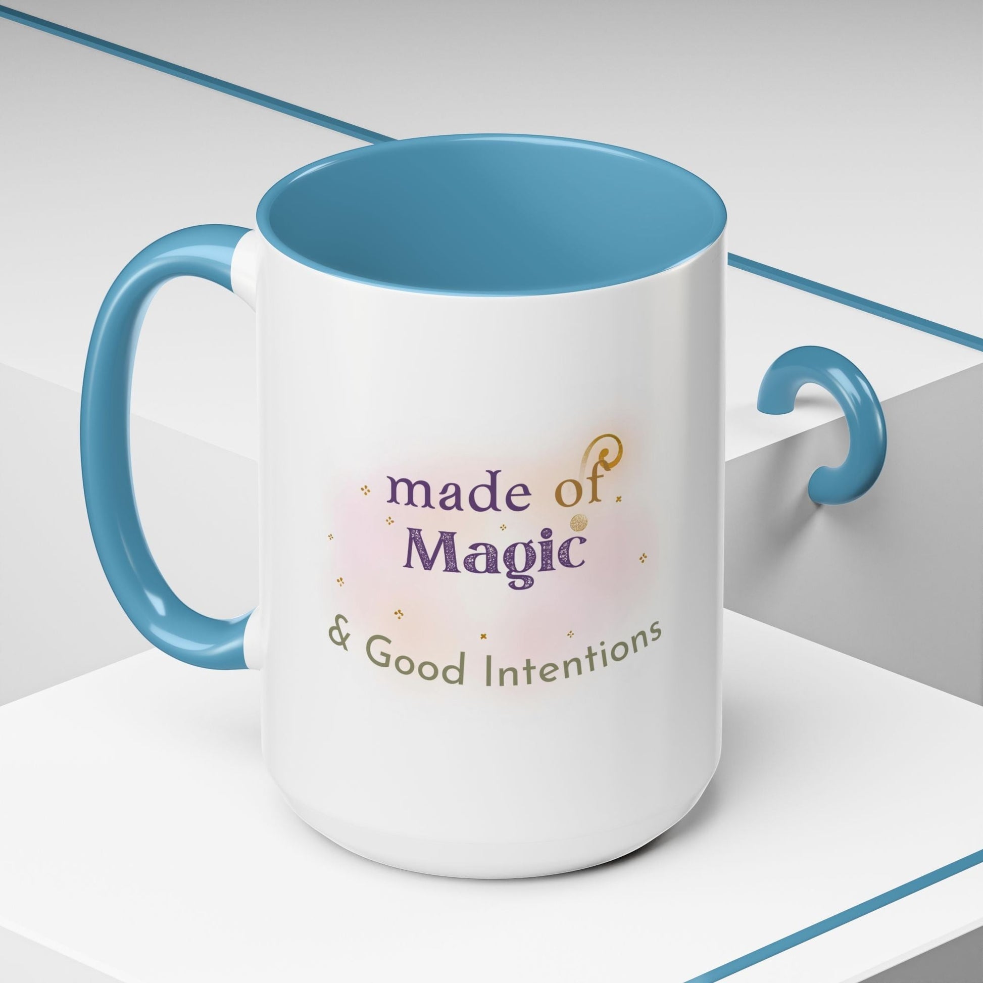 Jena Jewelry white ceramic mug with blue interior and handle, featuring "Made of Magic & Good Intentions" text and watercolor design.