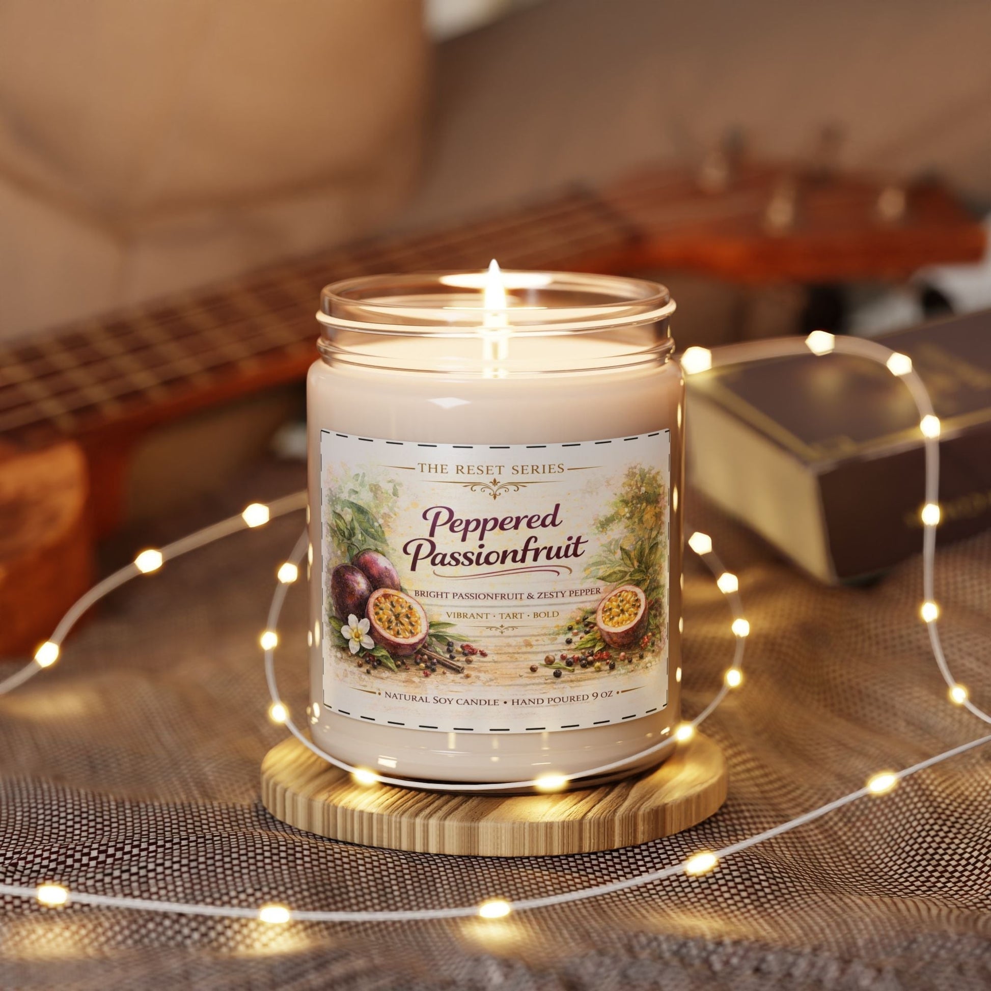 Jena Jewelry Peppered Passionfruit natural soy candle in a glass jar with a lit wick, on a wooden coaster, surrounded by fairy lights.