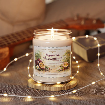 Jena Jewelry Peppered Passionfruit natural soy candle in a glass jar with a lit wick, on a wooden coaster, surrounded by fairy lights.