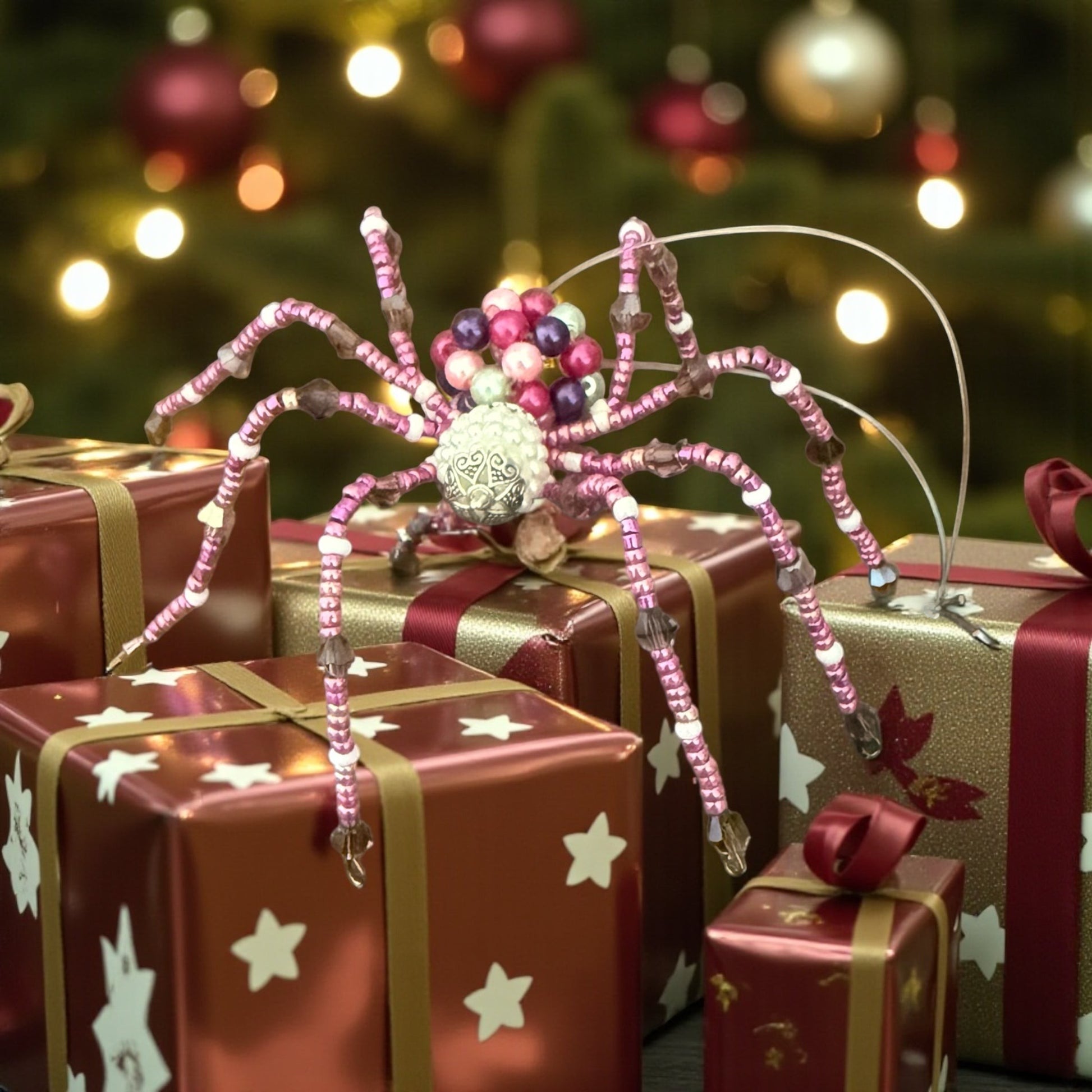 Jena Jewelry pink beaded spider ornament with a silver body, surrounded by Christmas gifts.