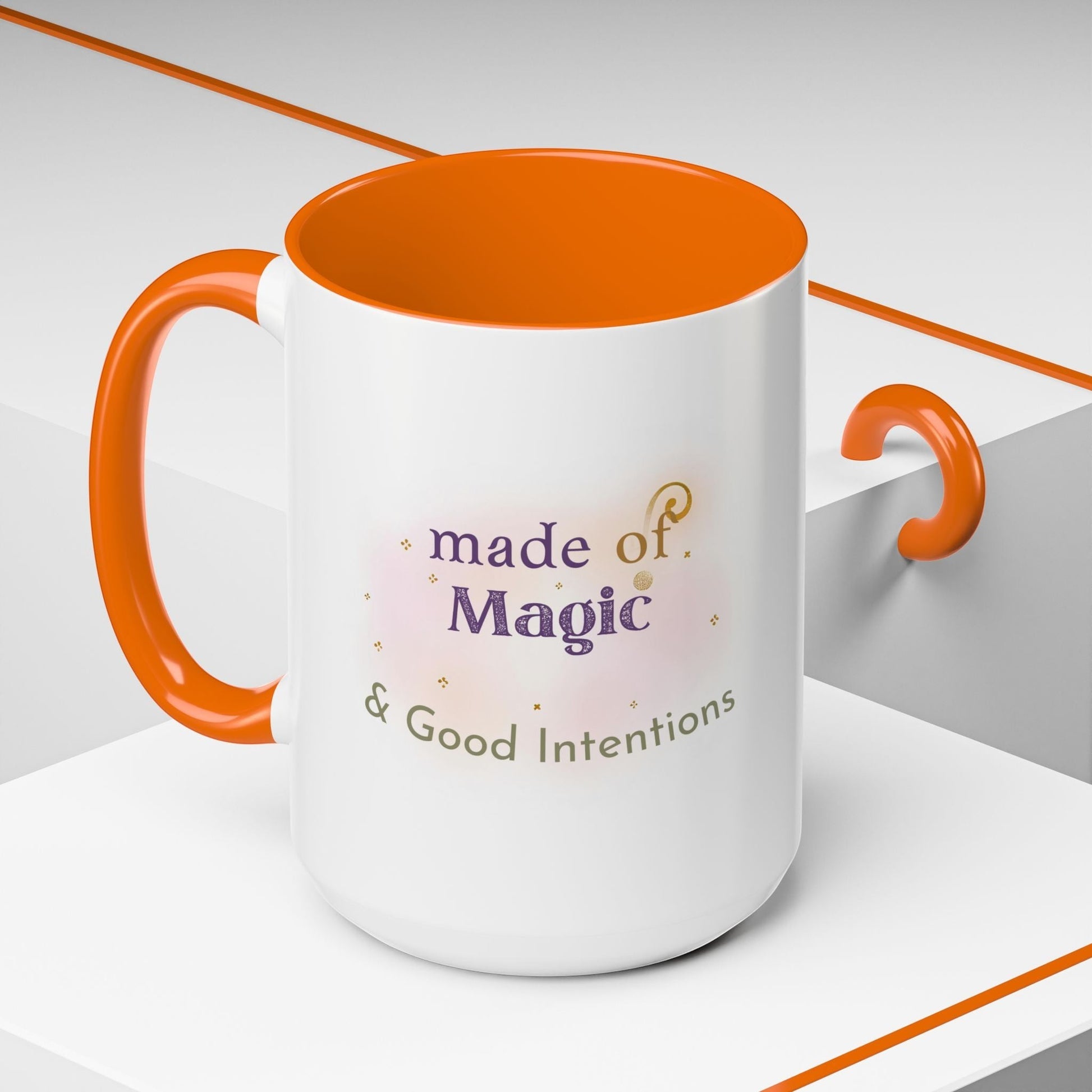 Jena Jewelry white ceramic mug with orange handle and interior, featuring "made of Magic & Good Intentions" text and watercolor accents.