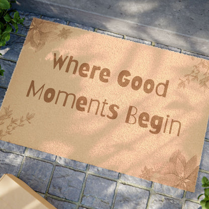 Jena Jewelry beige coir doormat with "Where Good Moments Begin" text and floral accents. Outdoor entryway decor.