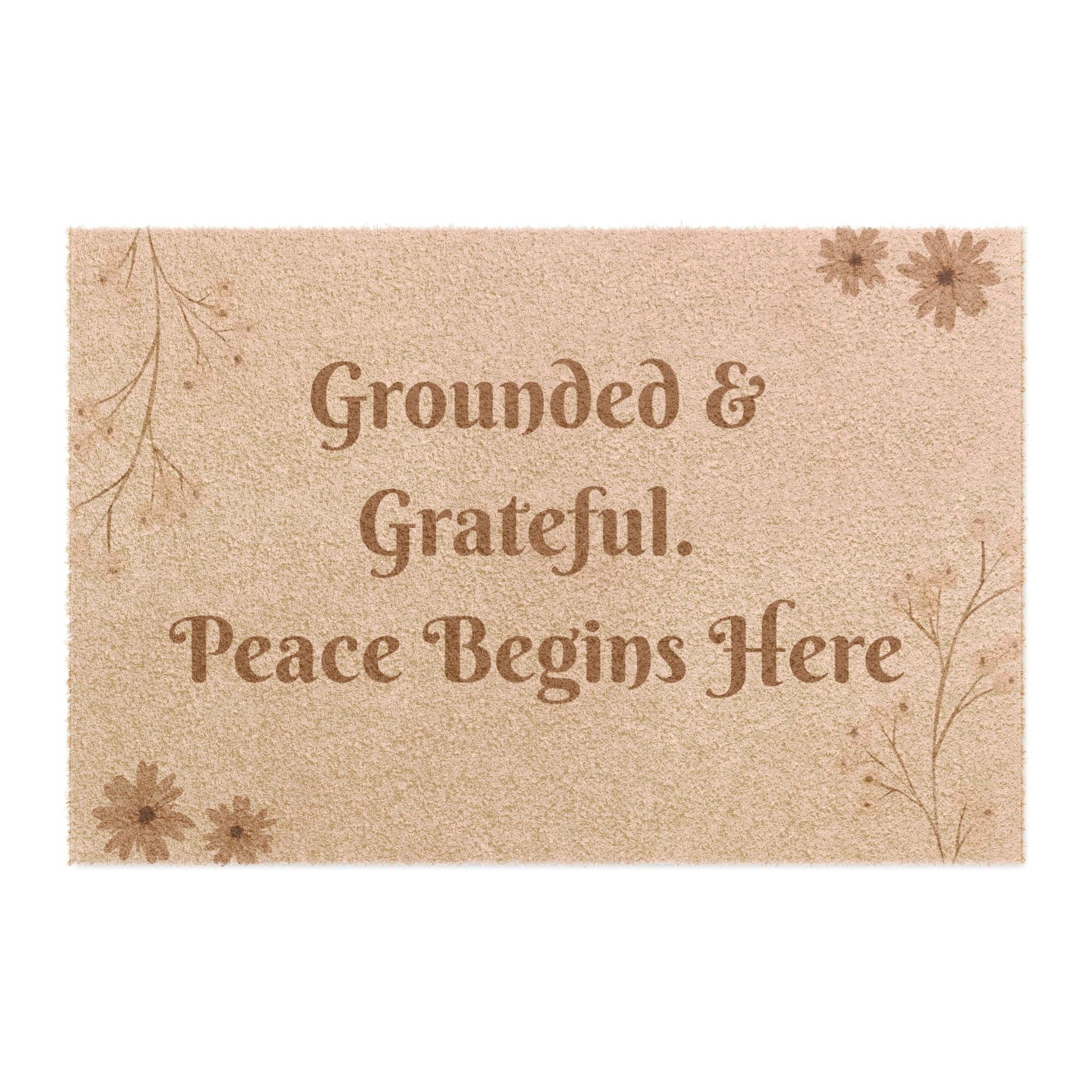 Jena Jewelry beige coir doormat with "Grounded & Grateful. Peace Begins Here" text and floral accents.