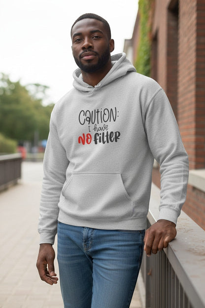 Man wearing grey “Caution I Have No Filter” hoodie outdoors, a stylish and humorous streetwear look.