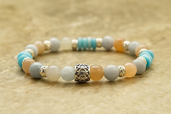 Moonstone & Angelite Stretch Bracelet contains peach and white round beads, disk-shaped sky-blue beads with silver-plated spacers on stretch cord